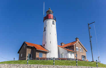 Fototapeta na wymiar White lighthouse and houses on the top of the dike in Urk, Netherlands