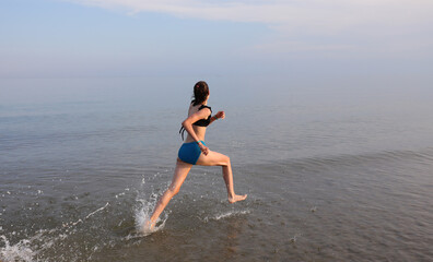 girl running on sea water in summer during sports training