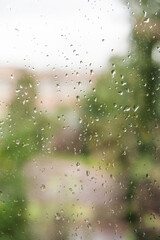 Rain drops on the window with blurred green trees in background