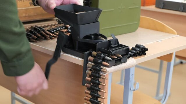 Machine for loading bullets in a iron metal belt line. Close up view.