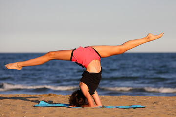 young slender athletic girl does exercises on gym mat on the beach