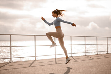 beautiful shot of one caucasian woman running and jumping. Female exercising outdoors.