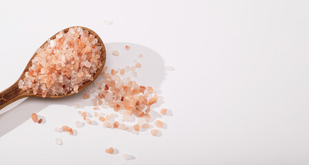 Himalayan pink salt, coarse, in a wooden spoon on a white background, place for text, banner