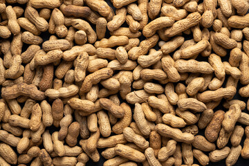 Background of dry unshelled peanuts, top view