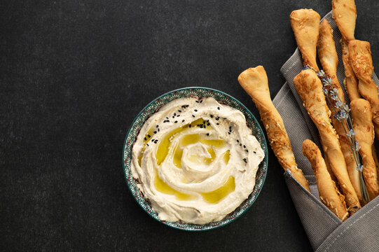 Classic hummus, finished dish decorated with sesame seeds, served with grisini bread sticks, top view