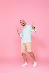 cheerful young happy man dance on pink background.