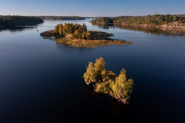 Small rocky island overgrown with trees in archipelago of many islands on Ladoga Lake Karelia Russia