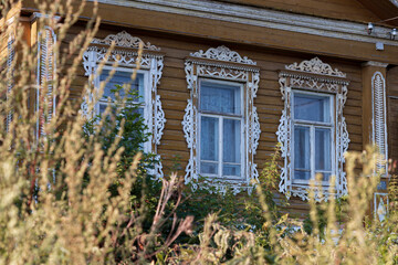 Fototapeta na wymiar Windows of a wooden Russian village house with traditional carved wooden trim, Plyos, Russia