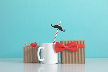 Happy Father's Day. Mug tea coffee and red bow tie, mustache, gift box on blue table, background....