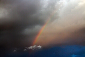 Fototapeta na wymiar Beautiful rainbow in a cloudy sky with clouds 