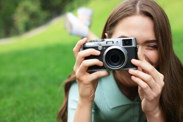Young woman with camera taking photo outdoors, space for text. Interesting hobby