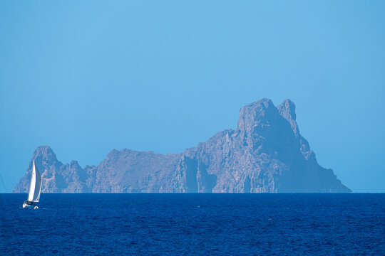 White sailboat sailing the sea with Es Vedra in the background