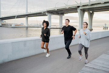 Friends run around in sportswear and sneakers. The concept of people's sports in the city.