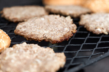 Burger patty on grill. Grilled Meat Cutlets cooking on metal grid for hamburger. Home barbeque party. Homemade hamburger.