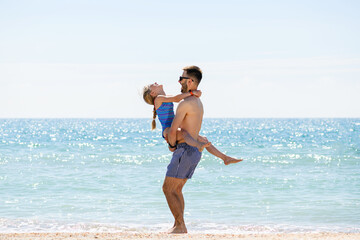 Fototapeta na wymiar Young father play with daughter at sea beach