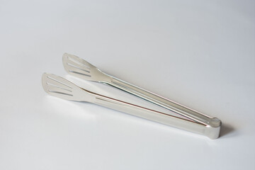 chromed kitchen tongs on an isolated white background