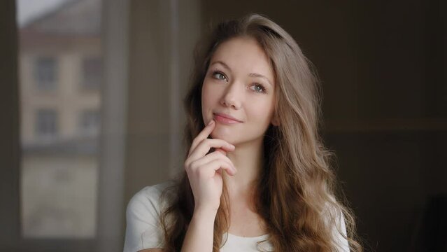 Close-up young pretty dreamy woman standing indoors dreaming about future thoughtful calm cute girl thinks remembers pleasant moments smiles pensive female searching inspiration for creative ideas