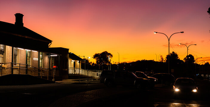 Horizontal image of train station at nightfall with cars leaving
