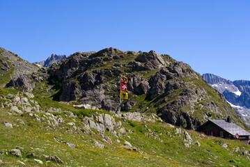 Swiss flag and flag of Canton Uri waving at Swiss mountain Pass Sustenpass on a sunny summer day. Photo taken July 13th, 2022, Susten Pass, Switzerland.