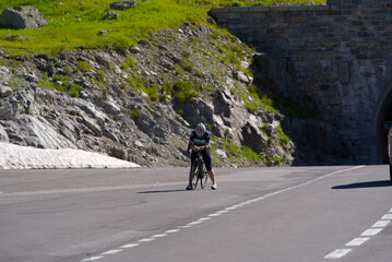 Fototapeta premium Exhausted woman racing cyclists just arrived at summit of Swiss mountain pass Susten on a sunny summer day. Photo taken July 13th, 2022, Susten Pass, Switzerland.