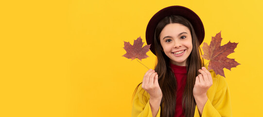 happy child in hat and coat with autumn maple leaves on yellow background. Autumn fall child for...