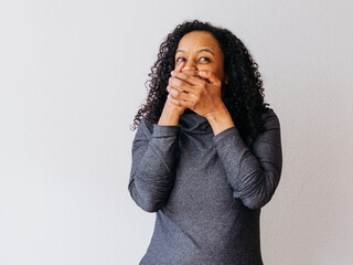 A young black girl showing strong emotions and closing mouth with her hands