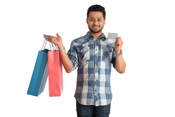 young man holding and posing with shopping bags with credit or debit card on a white background