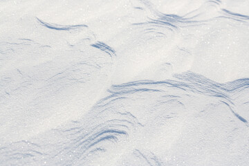 Beautiful winter background with snowy ground. Natural snow texture. Wind sculpted patterns on snow surface.