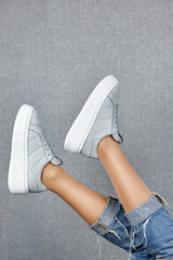 Young woman in blue jeans trying on gray sport shoes in shop, copy space. Woman wearing comfortable...