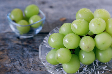 古い木のテーブルの上にガラスの小鉢に入ったぶどう