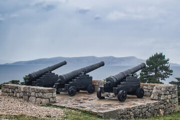 cannon in the fortress pointing at the sea with mountains in background