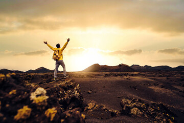 Happy man with arms up on a mountain at sunset - Traveler with backpack hiking nature -...