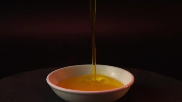 Slow motion close-up Steps to prepare food. golden ghee gradually pour into a white plate with meticulousness.food background