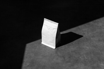Blank packaging doy pack coffee mockup, on concrete background, with sharp natural sunlit shadows....