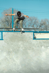 Skater boy riding his skateboard at the top of concrete bowl of skate park. Vertical photo.