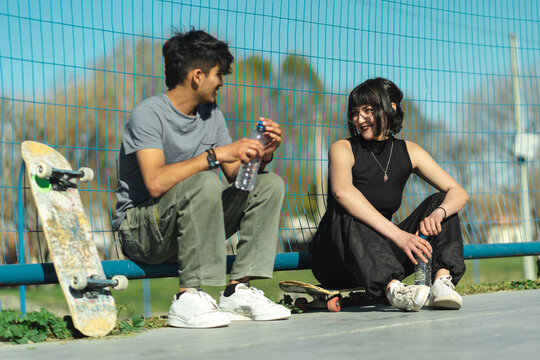 Close Up Of Teenage Skaters Talking And Resting In The Park. Selective Focus