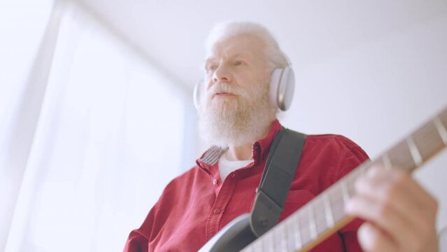 Closeup of senior man learning to play the guitar, popular hobby, rock and roll