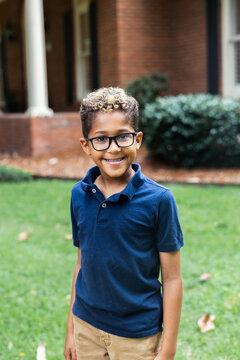 Waist up image of a cute african american boy with glasses and a big smile