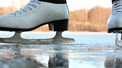 Woman wearing white figure skates skating at frozen lake ice. surface. Winter outdoor sport activities