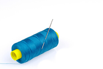 Macro skein of blue thread with a needle on a white background