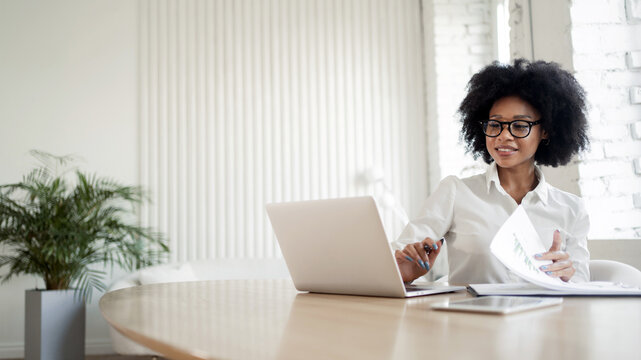 A female secretary working on a project online uses a laptop.