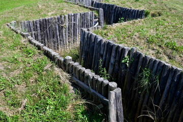A close up on a wooden trench or walkway made out of sticks, logs, and planks allowing to travel through a tall hill seen on a sunny summer day on a Polish countryside in summer 