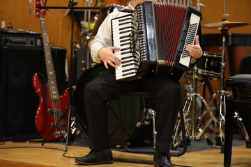 An accordion player boy plays a musical instrument performing on stage at a school concert