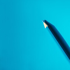 Blue pencil on a blue paper background with space for text. Creativity, studying, and business ideas