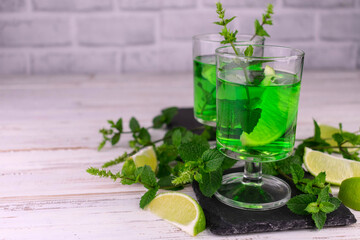 Mint liqueur with lime in glasses on a black board for serving.Copy space.
