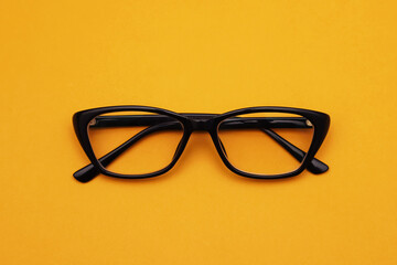 Glasses with diopters in a black frame on an orange background. Close-up