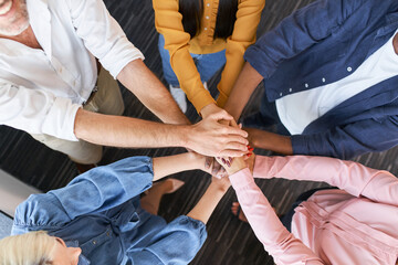 Close up of coworkers stacking hands together at office. Business people team building concept.