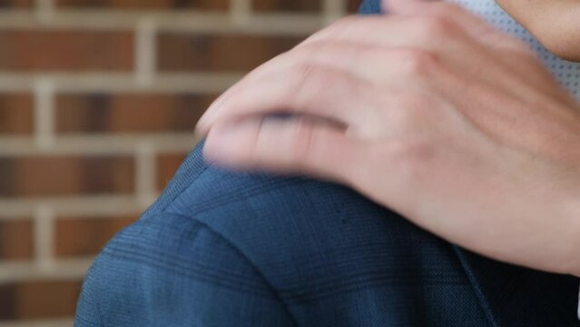Unrecognizable man shaking off dandruff from his shoulder, close-up