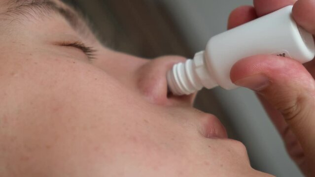 A man drips medicine into his nose, close-up