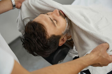 Caring barber removing foam from guest face with towel